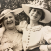 Historical 1937 black and white photograph of Stella Elkins Tyler wearing a wide-brimmed hat and vintage dress smiling with a companion outdoors