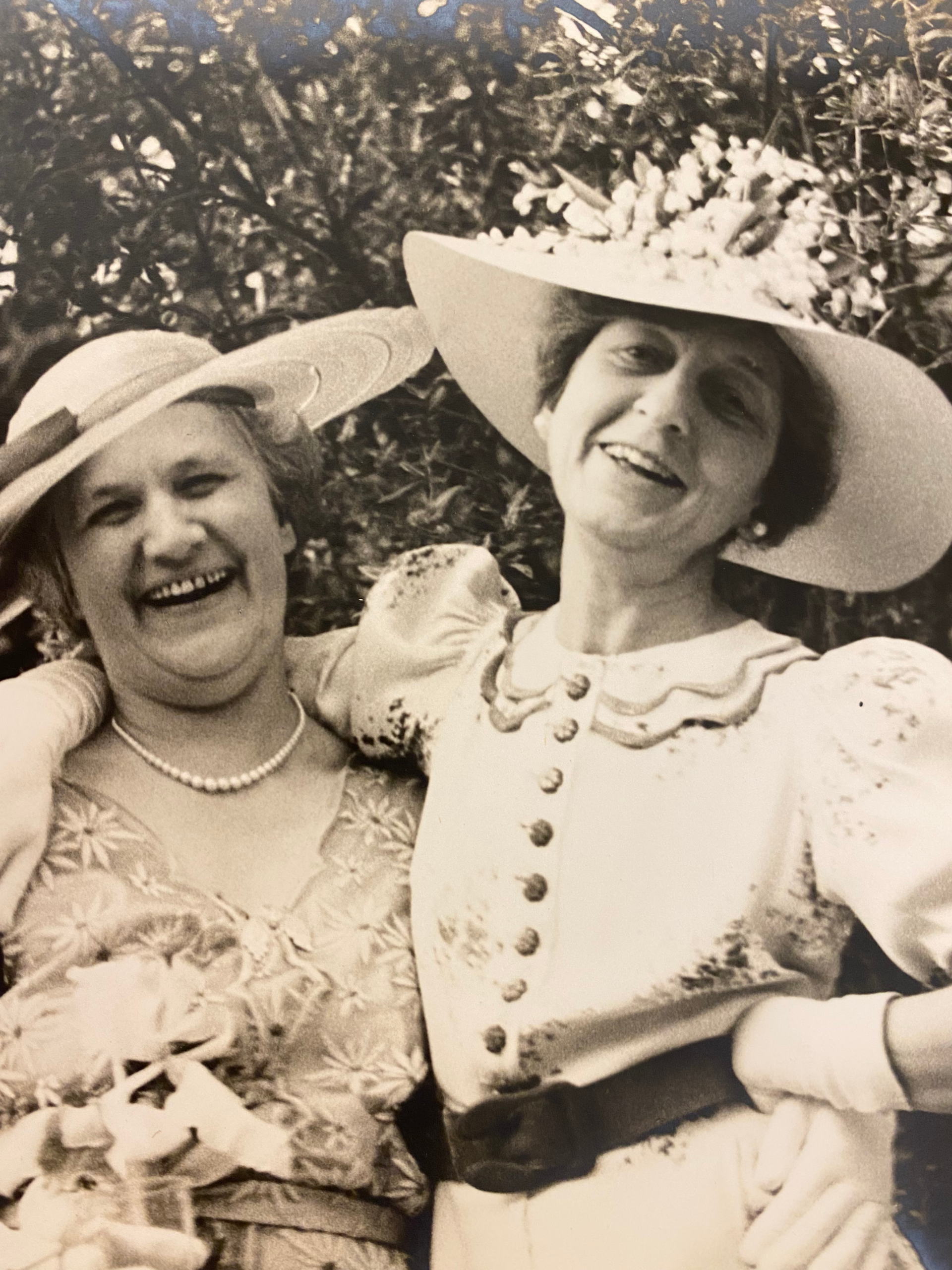 Historical 1937 black and white photograph of Stella Elkins Tyler wearing a wide-brimmed hat and vintage dress smiling with a companion outdoors